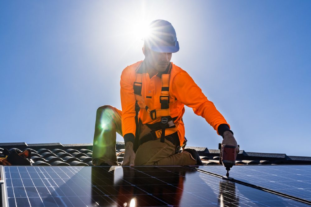 Image of a man on a roof with solar panels.